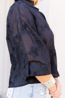 Black embroidered blouse worn by a person on a white background