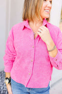 Woman wearing a bright pink button-up shirt, standing against a neutral background.