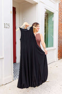 Woman holding a black dress on a hanger outside Laundry Dae boutique.
