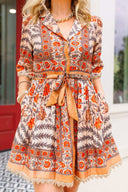 Woman wearing a patterned dress with a belt in an outdoor setting