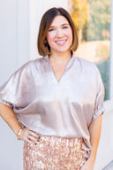Woman wearing a champagne metallic top and rose gold sequin skirt.