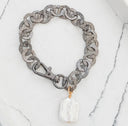 Gray chain bracelet with a clear crystal charm on a marble surface