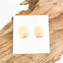 Gold earrings on a Luxe by Venna card with a wooden background