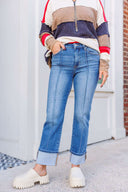 Person wearing a red, white, and blue sweatshirt and medium wash jeans with chunky ivory slide shoes.