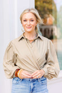 Woman wearing a beige blouse and blue jeans with a blurred outdoor background