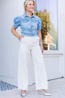 Woman wearing a denim shirt and ivory twill pants.