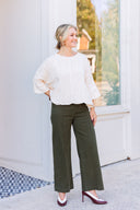 Woman wearing an ivory cable knit sweater and olive green pants.
