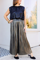 Pleated metallic wide leg pants with black sleeveless satin top.