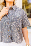 Woman wearing a cheetah shirt and white jeans standing in front of a building.