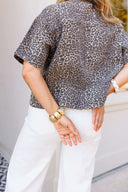 Woman wearing a leopard print shirt standing in front of a building.