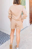 Person wearing a beige shorts set walking on a sidewalk.
