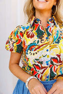 Person wearing a colorful patterned shirt and blue denim bubble skirt with a blurred background