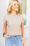 Woman wearing a beige top and blue jeans outdoors