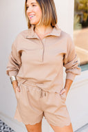 Woman wearing a beige outfit with a matching shirt and shorts.
