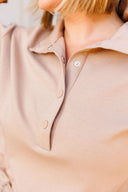 Close-up of a beige shirt with a collar and snaps.