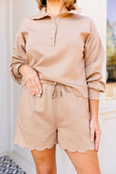 Person wearing a beige outfit with a matching shirt and shorts.