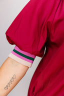 Crimson dress with striped trim on a plain background