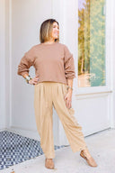 Woman in a brown sweatshirt and beige corduroy pants standing outside Laundry Dae Boutique. 