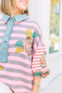 Person wearing a pink and gray striped shirt with a boho floral design.