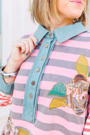 Person wearing a pink and gray striped shirt with a boho floral design.