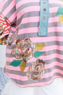 Person wearing a pink and gray striped shirt with a boho floral design.
