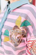 Person wearing a pink and gray striped shirt with a boho floral design.