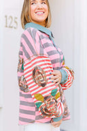 Person wearing a pink and gray striped shirt with a boho floral design.
