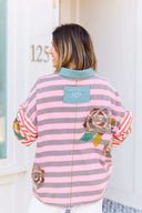 Person wearing a pink and gray striped shirt with a boho floral design.