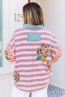 Person wearing a pink and gray striped shirt with a boho floral design.