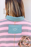 Person wearing a striped shirt with a smiley face patch on the back