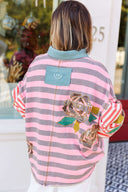 Person wearing a pink and gray striped shirt with a boho floral design.