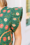 Woman wearing a green floral vest standing outside boutique.
