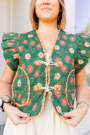 Woman wearing a green floral patterned top with a blurred background