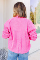 Person wearing a bright pink jacket with a blurred outdoor background