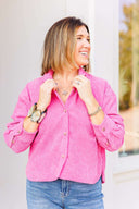 Woman wearing a pink corduroy shirt and blue jeans outdoors