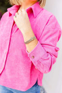 Person wearing a bright pink corduroy shirt, close-up on arm.