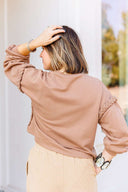 Woman wearing a brown sweatshirt and beige pants outdoors