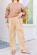 Woman in a brown sweatshirt and beige corduroy pants standing outside Laundry Dae Boutique. 