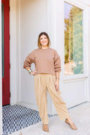 Woman in a brown sweatshirt and beige corduroy pants standing outside Laundry Dae Boutique. 