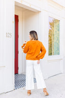 Woman wearing a toffee sweatshirt with white ribbon detail standing in front of Laundry Dae Boutique.