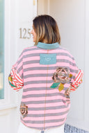 Person wearing a pink and gray striped shirt with a boho floral design.