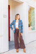 Woman in white tank top, blue plaid blazer, and brown jeans standing outside Laundry Dae Boutique.