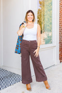 Woman in white tank top and brown jeans standing outside Laundry Dae Boutique.