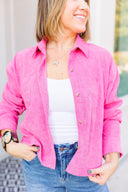 Woman wearing a bright pink jacket over a white top and blue jeans.