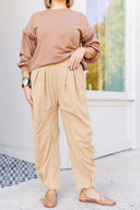 Woman in a brown sweatshirt and beige corduroy pants standing outside Laundry Dae Boutique. 