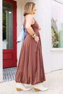 Woman wearing a brown dress standing outside  Laundry Dae boutique.
