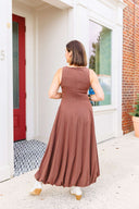 Woman in a brown dress standing outside Laundry Dae boutique.