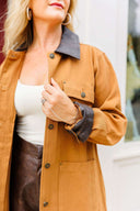 Person wearing a brown jacket with a white top and brown pants.
