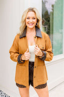Woman wearing a camel jacket with brown faux leather collar accents.