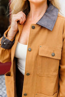 Close-up of a person wearing a brown jacket with a brown collar.